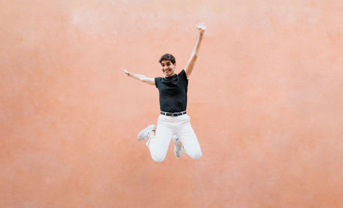 Cheerful man jumping against wall