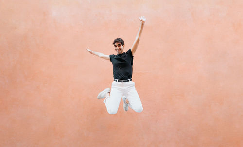 Rear view of man with arms raised standing against blue background