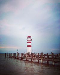 Lighthouse by sea against sky