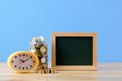 Close-up of clock on table against blue background