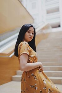 Low angle view portrait of beautiful young woman standing on staircase