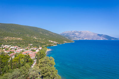 High angle view of townscape by sea against clear blue sky