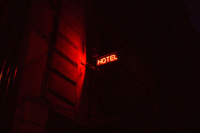 Low angle view of illuminated hotel sign on building at night