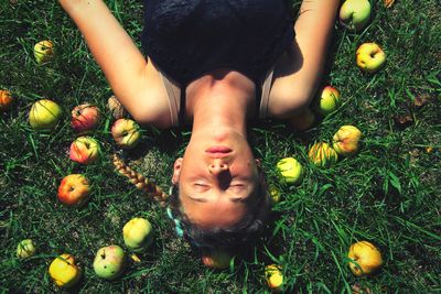 Directly above shot of young woman resting by apples on field