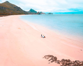 Friends sitting at beach against sky