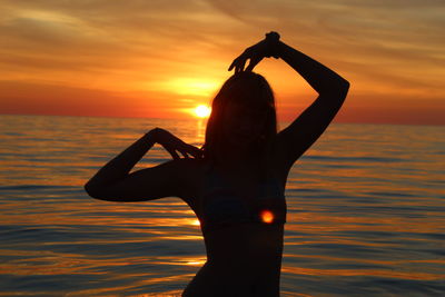 Silhouette man standing by sea against sky during sunset