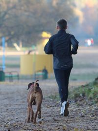 Rear view of man with dog standing in city