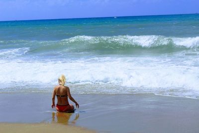 Rear view of shirtless man standing in sea