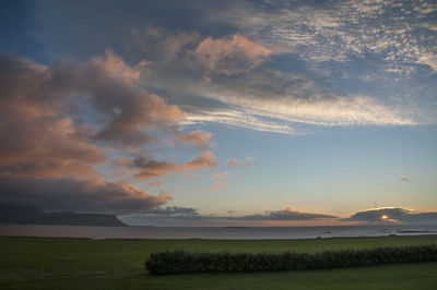 Scenic view of field against cloudy sky during sunset