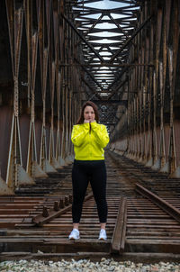 Full length portrait of woman standing on metal structure