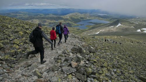 Rear view of people walking on mountain against sky