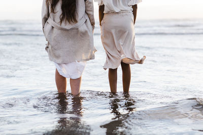 Low section of women standing on beach