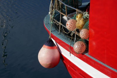 Red fishing ship moored with several pink buoys on its deck