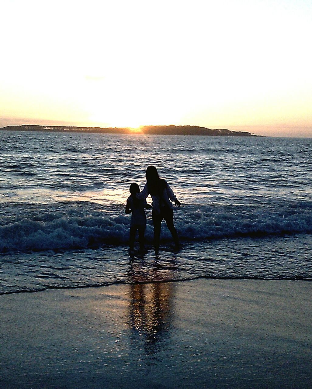 sea, water, horizon over water, sunset, beach, silhouette, leisure activity, shore, lifestyles, full length, reflection, men, scenics, vacations, sun, sky, tranquil scene, standing