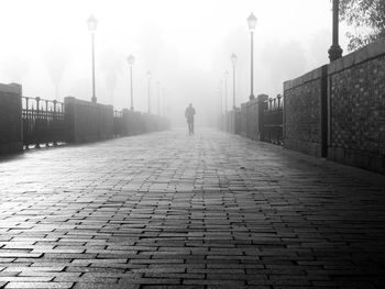 Rear view of man on cobblestone street against sky