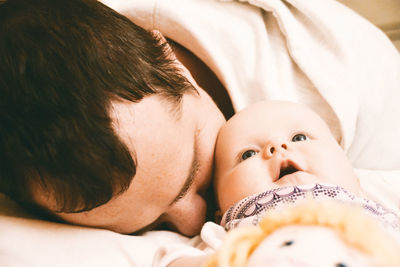 Close-up of man with toddler daughter lying on bed