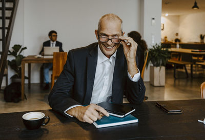 Portrait of smiling male entrepreneur with eyes at conference table in off