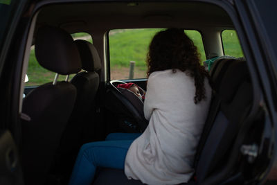 Rear view of woman and baby girl sitting in car