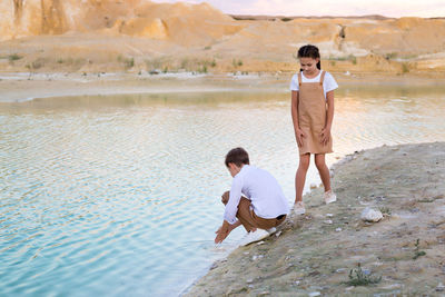 Rear view of woman standing on rock by lake