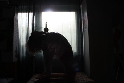 Rear view of woman sitting in window at home