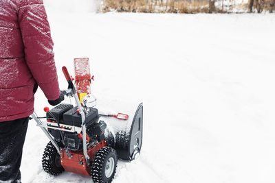 Detail of portable red snow blower powered by gasoline in action. man outdoor use snowblower machine