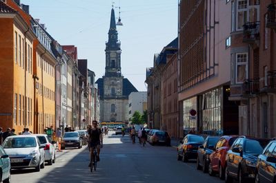 Man cycling on road against historic building