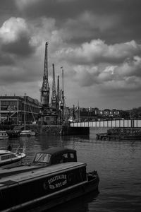 Sailboat at harbor against cloudy sky