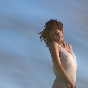 Portrait of young woman sitting against sky