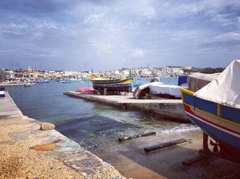 Boats moored at harbor against sky