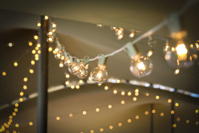 Low angle view of illuminated light bulbs on string during party