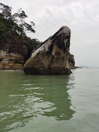 Rock formation in sea against sky