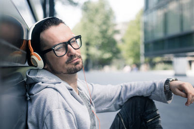 Man listening music while sitting on footpath