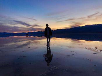 Man standing on beach against sky during sunset