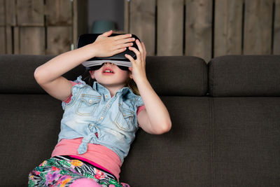 Full length of girl sitting on sofa at home