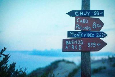 Close-up of road sign by sea against sky