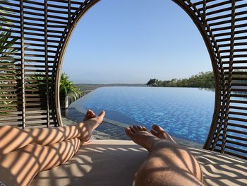 Low section of person relaxing on sea against clear sky