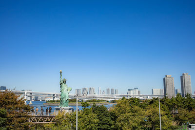 Trees and buildings against clear blue sky