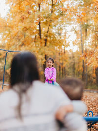 Rear view of woman sitting on footpath during autumn