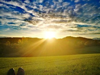 Low section of person on field against sky during sunset