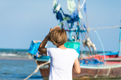 Rear view of woman on boat in sea against clear sky