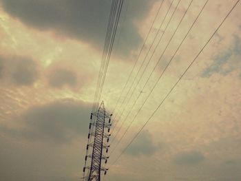 Low angle view of electricity pylon against cloudy sky