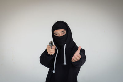 Portrait of young woman standing against white background