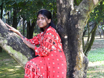 Portrait of young woman standing against trees