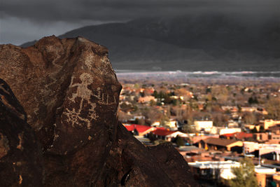 Close-up of rock by cityscape against sky