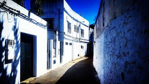 Road amidst buildings against blue sky