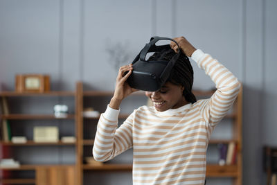 Inspired afro woman at home put on vr helmet to enjoy virtual reality online game cyber simulation