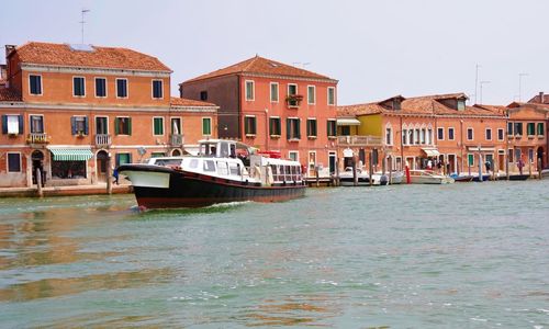 Boats in canal by buildings against sky