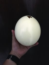 Close-up of hand holding apple against black background