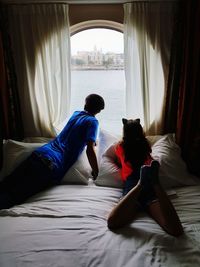 Siblings on bed looking through window