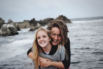 PORTRAIT OF SMILING YOUNG WOMAN AT BEACH